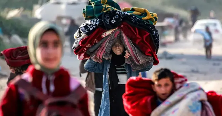 যুদ্ধে নির্মূল হয়ে যাওয়াদের সাথে একটি মেয়ে মাথায় ব্যাগ নিয়ে হাঁটছে